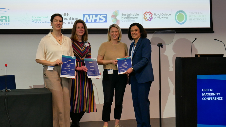 Three people standing on stage, holding certificates, with RCOG President, Ranee Thakar